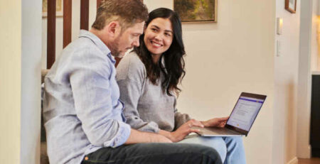 A man and woman work together on a laptop.