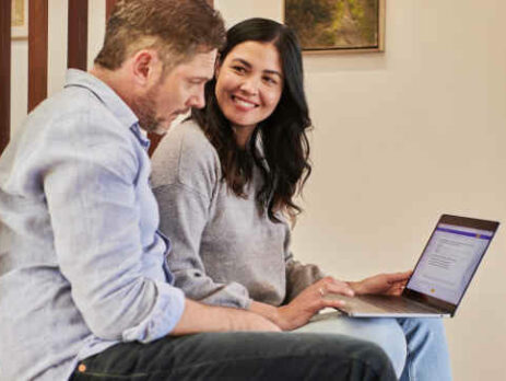 A man and woman work together on a laptop.