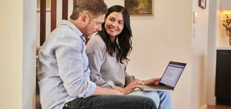 A man and woman work together on a laptop.