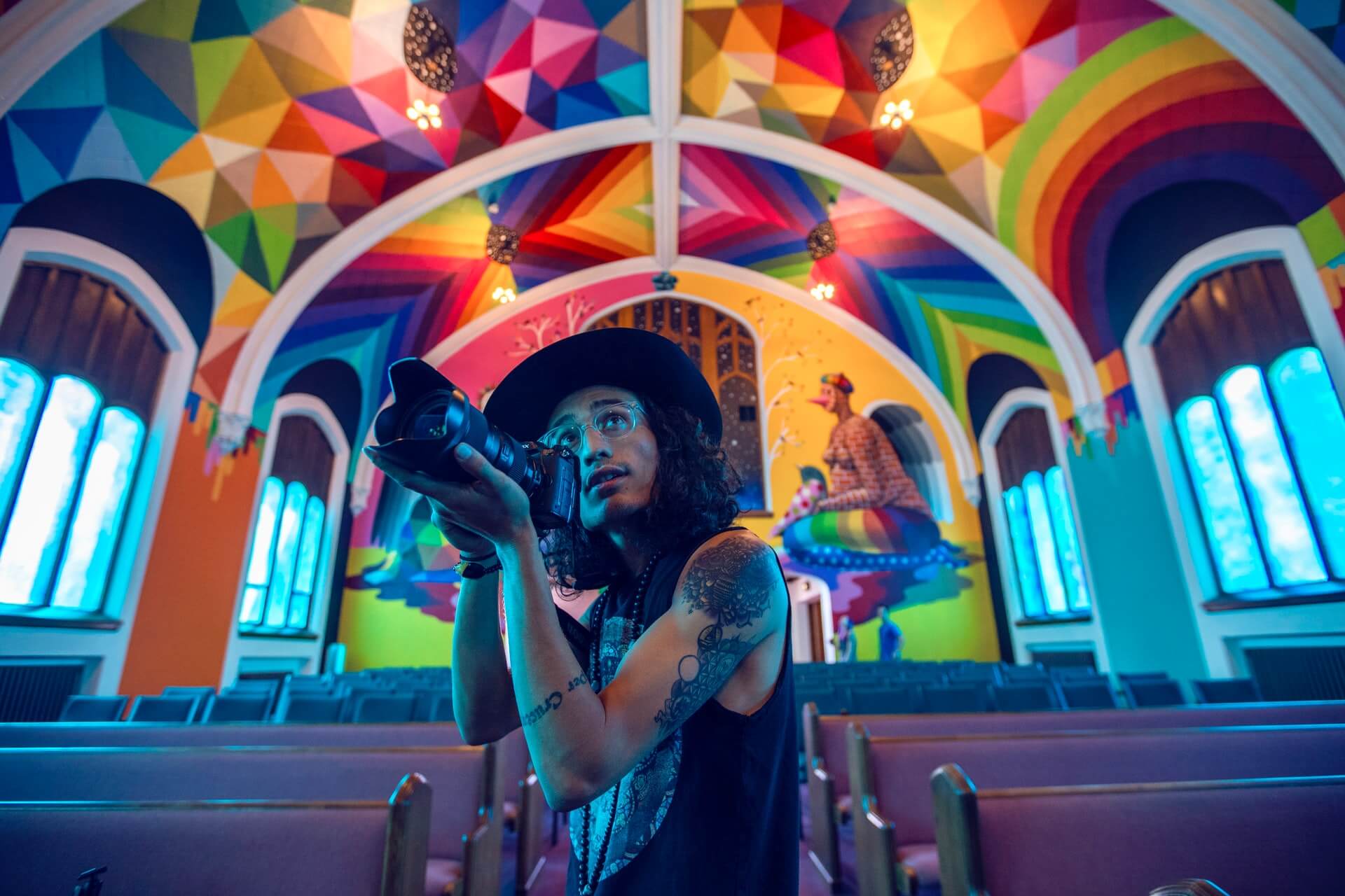A man with a camera takes pictures underneath a colorful ceiling.