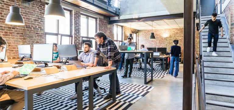 People work on laptop computers in an office.