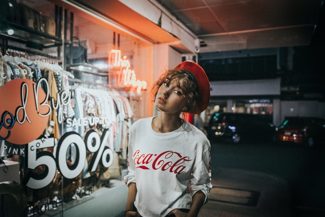 A woman in a red hat stands in front of a shop window