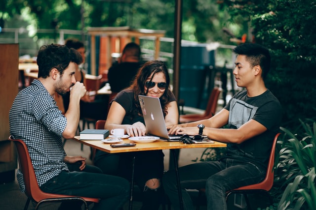 Two men and a woman work at a coffee shop.