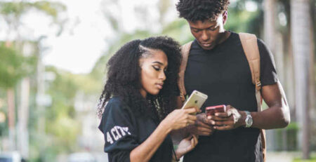 A man and woman compare smartphones with one another.