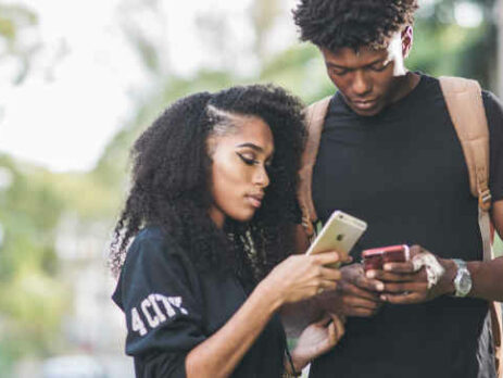 A man and woman compare smartphones with one another.