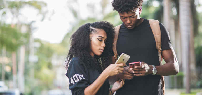 A man and woman compare smartphones with one another.