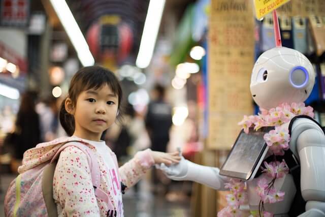 A girl interacts with a white robot.