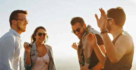 A group of people standing together laughing in the sunshine.