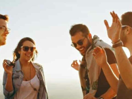 A group of people standing together laughing in the sunshine.