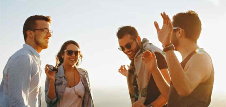 A group of people standing together laughing in the sunshine.