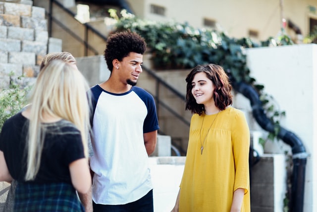 Four people stand outside talking to each other.