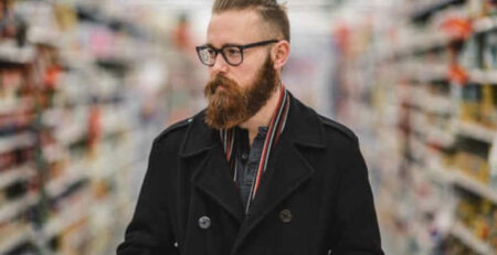 A bearded man shopping in a supermarket.