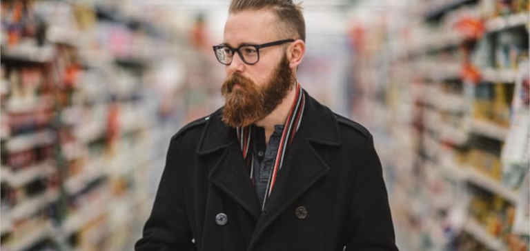 A bearded man shopping in a supermarket.