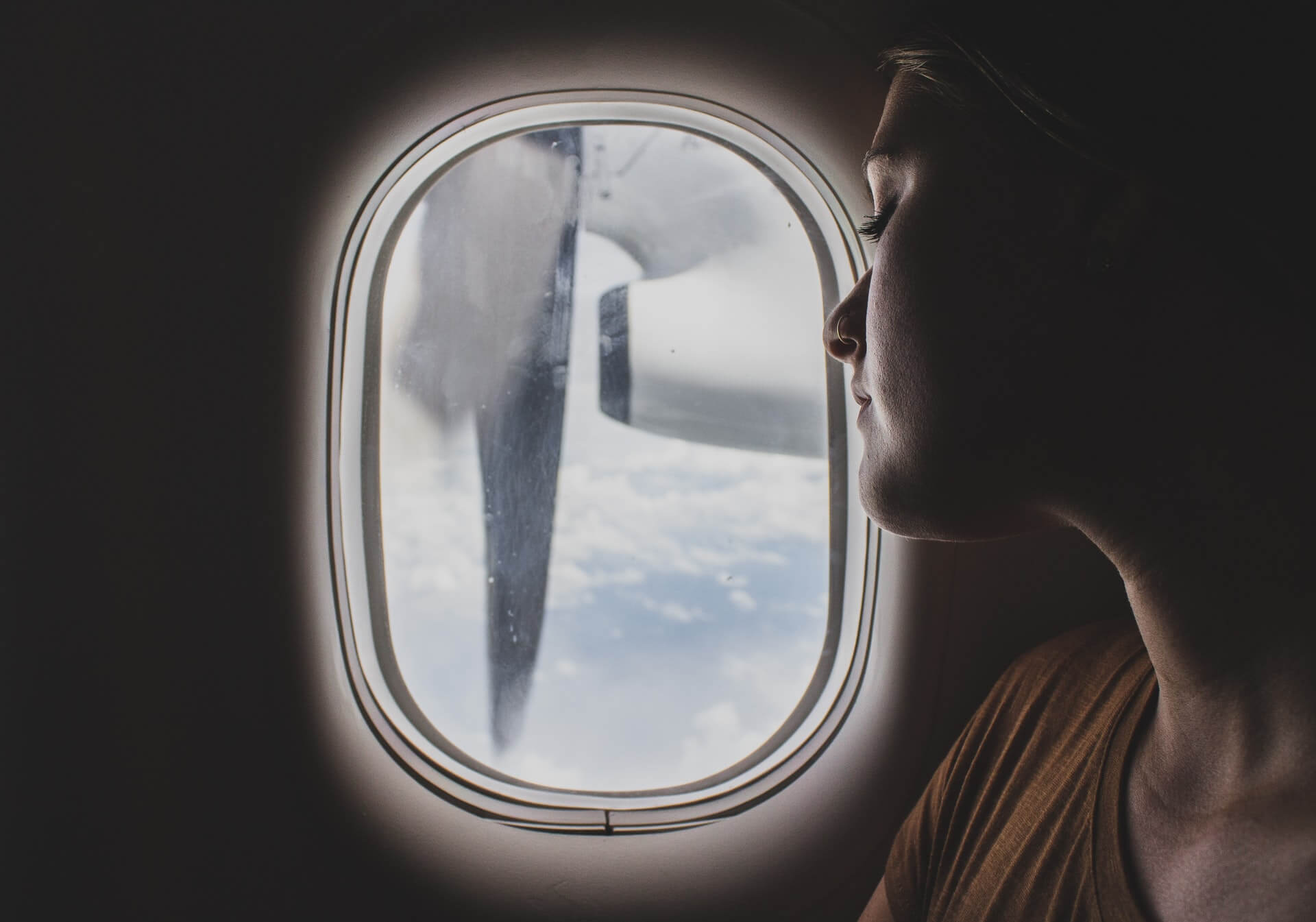 A woman looks out the window on an airplane.