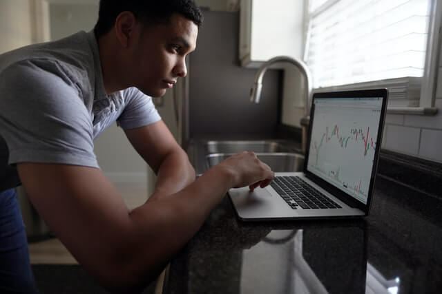 A man works on a laptop in the kitchen.