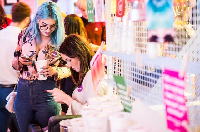 Two women on using smartphones in a shop.