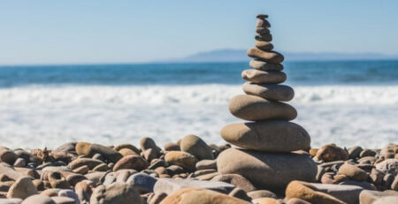 A tower of stones next to a beach on a sunny day.