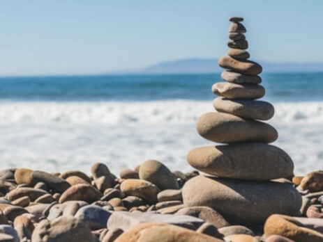 A tower of stones next to a beach on a sunny day.