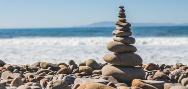 A tower of stones next to a beach on a sunny day.