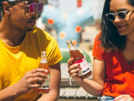 A man and woman sit in the sun with cold beverages.