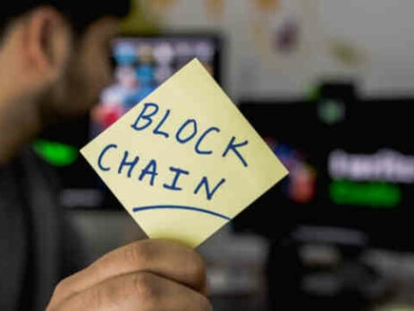 Someone holds a sticky note that says “blockchain” on it.