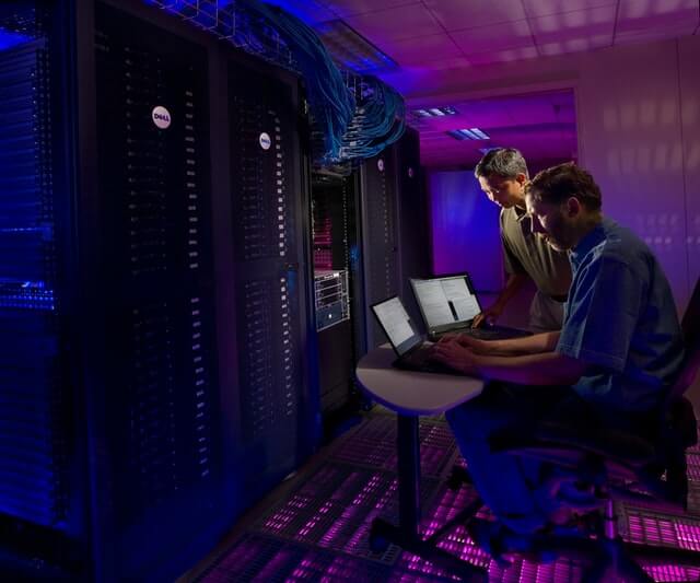 Two men work near a large data server.