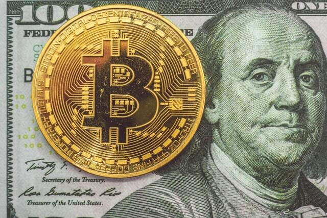 A bitcoin and a one hundred dollar bill.