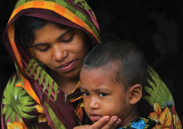 A woman sits with her child on her lap.