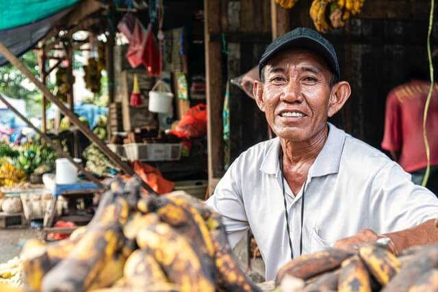 An old man sits near a shop.