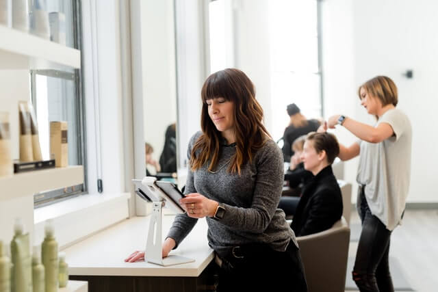 A woman works at a register while others work in the background.