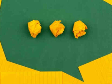 Three pieces of crumpled up yellow paper on a green background