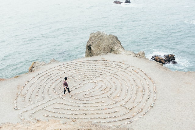 A person enters a rock maze on the beach.
