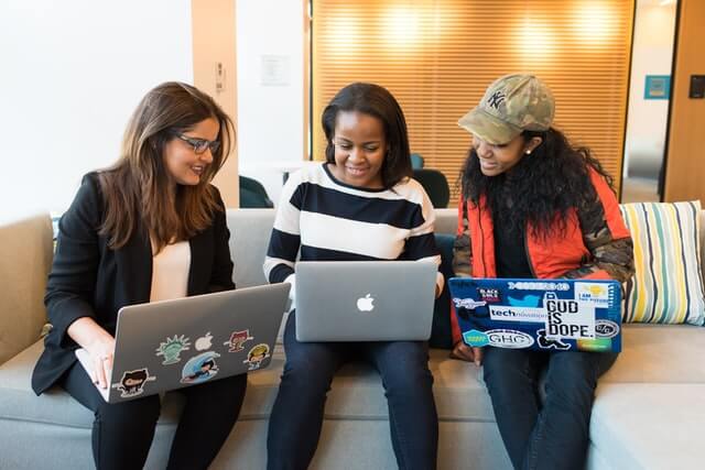 Three women work on laptop computers together.