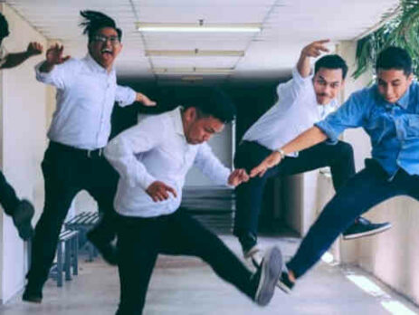 Business people jumping in the air in a hallway.