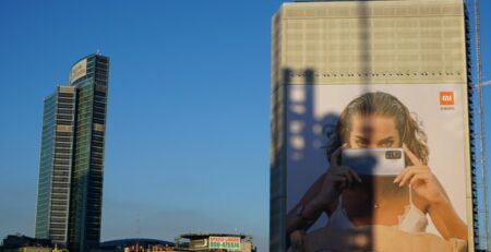 A cityscape and a billboard featuring a woman with a phone.