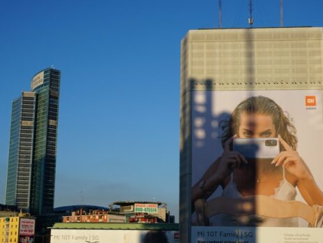 A cityscape and a billboard featuring a woman with a phone.
