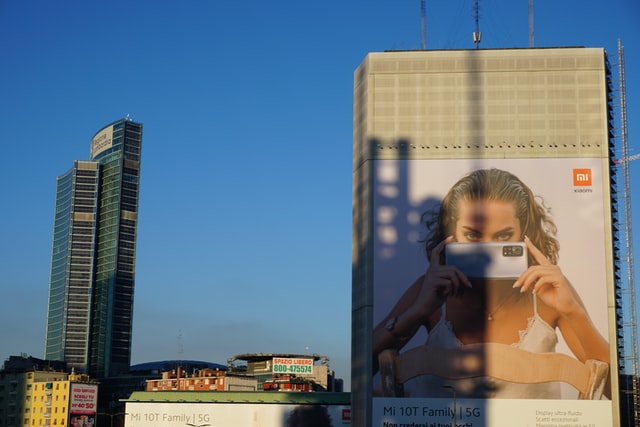 A cityscape and a billboard featuring a woman with a phone.