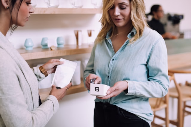 A woman scans a credit card with a white machine.