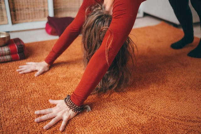 Someone in a red shirt stretches on the floor.