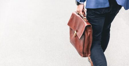 Someone in a blue suit jacket holding a suitcase.