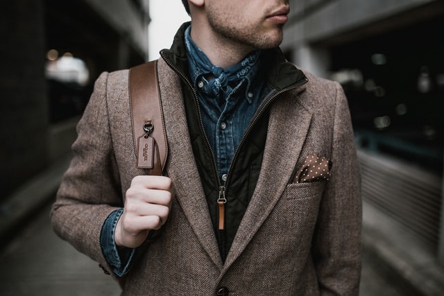 Someone stands wearing a blue shirt and a jacket.