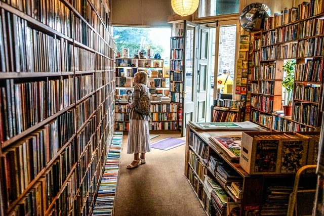 A woman stands in a bookshop looking at books.