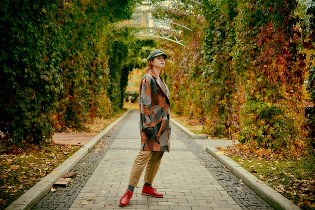 A girl in a green hat standing in the woods.