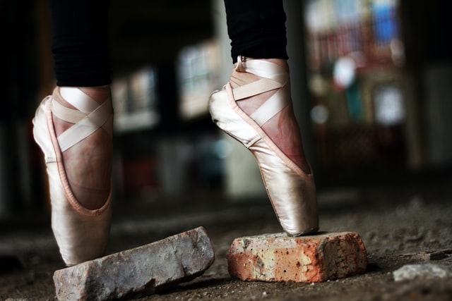 Two feet in ballerina slippers poised on platforms.