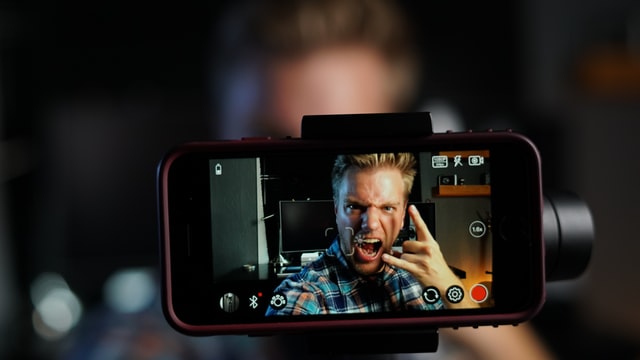 A man shows the rock-n-roll hand gesture on a smartphone screen.