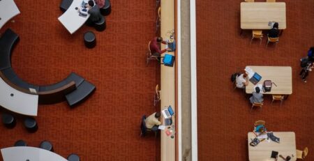 People sit in a library on computers.