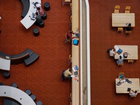 People sit in a library on computers.