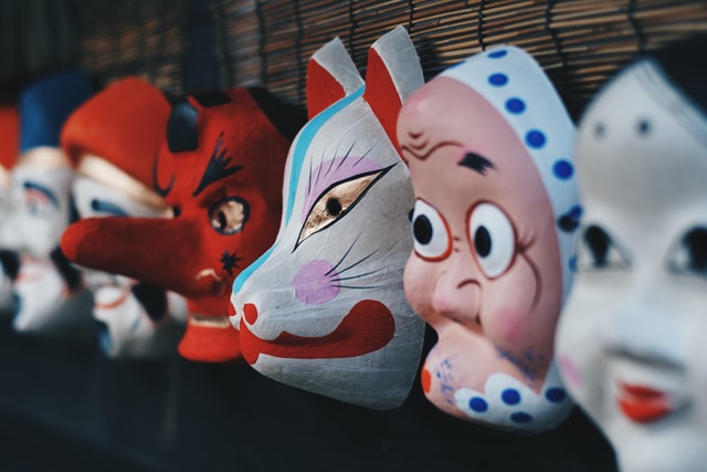 A row of colorful masks hang on a wall.