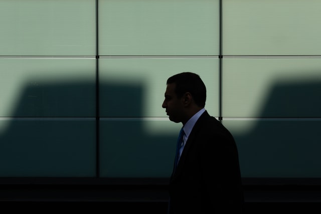 The shadow of someone in a suit and tie with light behind them.