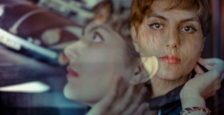 A double exposure of a woman with short hair in a turquoise shirt.